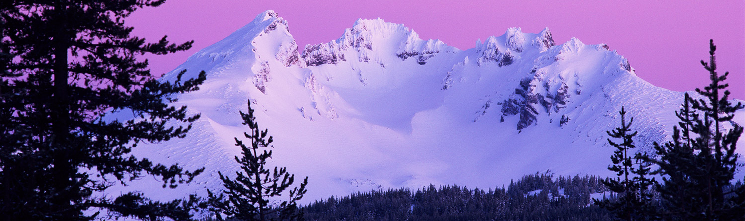 snowy peaked mountain with a pink sky