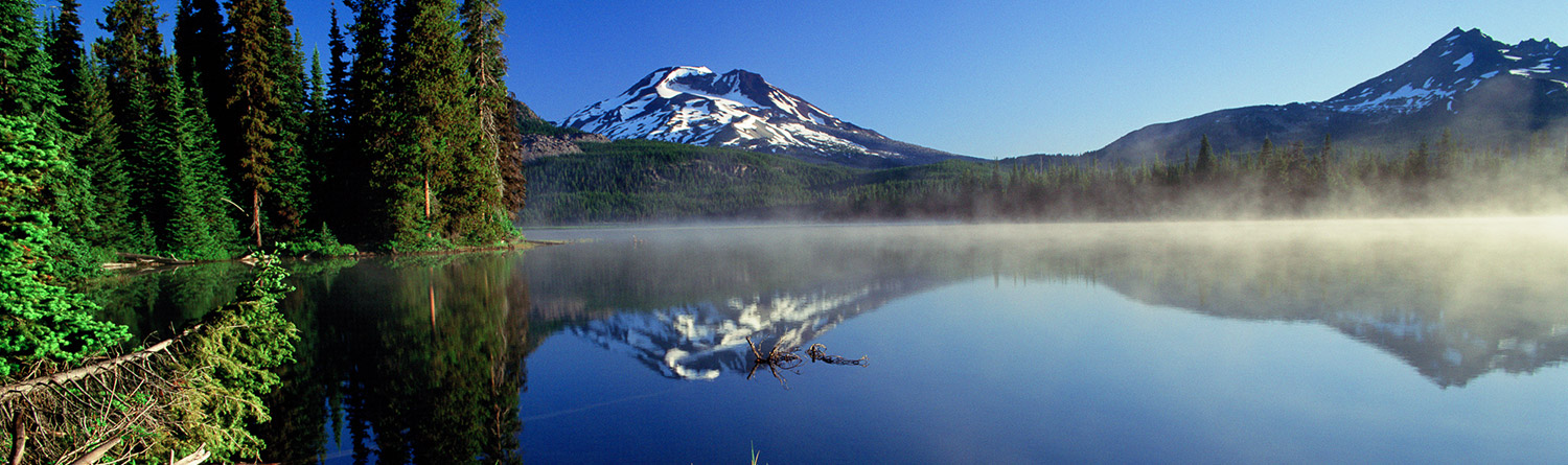 mountain reflected in a lake with green trees
